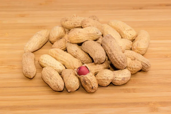 Amendoins assados em conchas em uma superfície de madeira — Fotografia de Stock