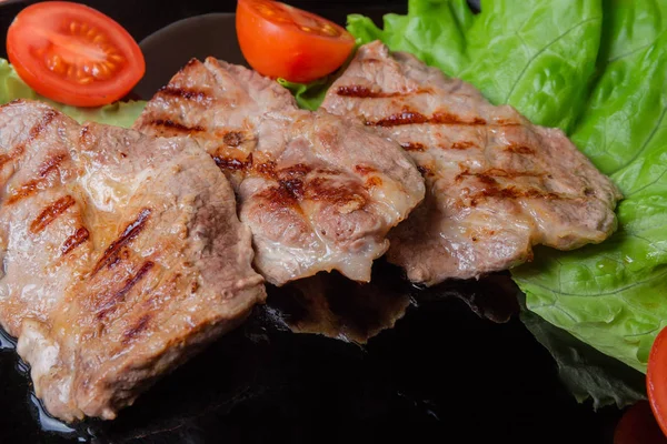 A közeli fekete tányér zöldséges nedvdús sertés steak grillezve — Stock Fotó