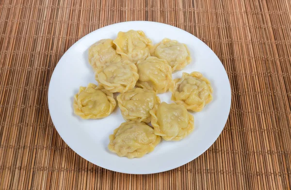 Gekookt zelfgemaakte vlees dumplings op schotel op bamboe tabel mat — Stockfoto