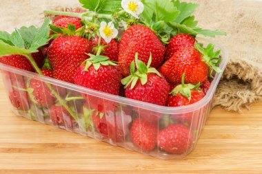 Plastik kap yakın çekim yaprakları ve çiçekleri ile çilek