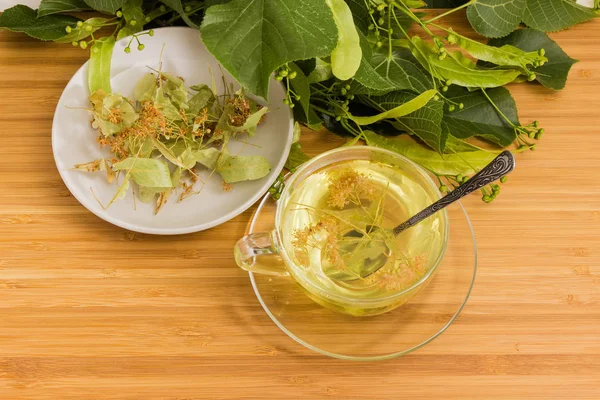 Чай Линден в стеклянной чашке, сушеные липовые цветы, липовые ветви — стоковое фото
