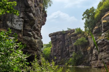 Yaz gününde kanyonda sakin nehir üzerinde sarkan kayalar