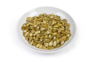 Beyaz arka planda tabak üzerinde soyulmuş kabak çekirdeği