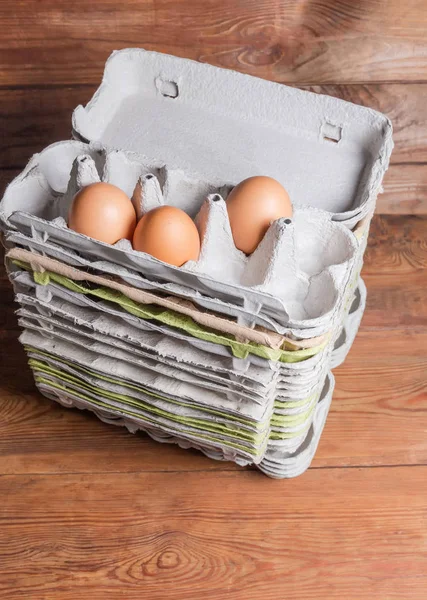 Stack of open pulp egg cartons with several chicken eggs