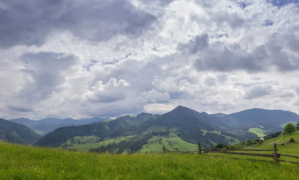 Bergketens met omheinde hooi velden op de voorgrond — Stockfoto