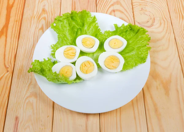 Metà di uova di pollo bollite su lattuga su piatto — Foto Stock