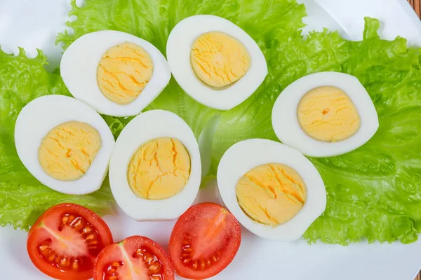 ครึ่งหนึ่งของไข่ไก่ต้มและมะเขือเทศเชอร์รี่บนผักกาดหอม — ภาพถ่ายสต็อก