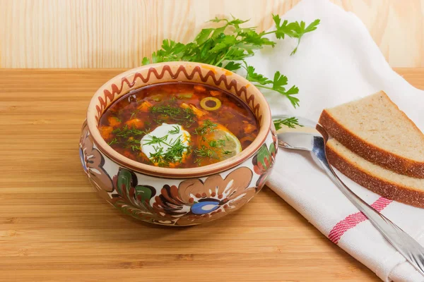 Meat solyanka in bowl, spoon and bread on wooden table — Stock Image Meat solyanka in bowl, spoon and bread on wooden table Royalty Free Stock Photos