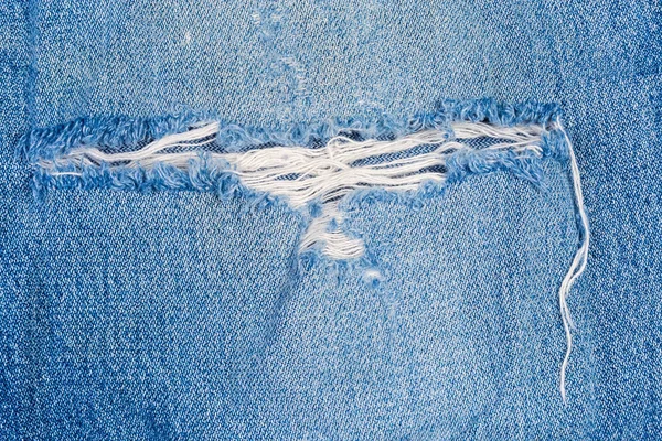 Hole on denim jeans with frayed threads close-up — Stock Photo, Image