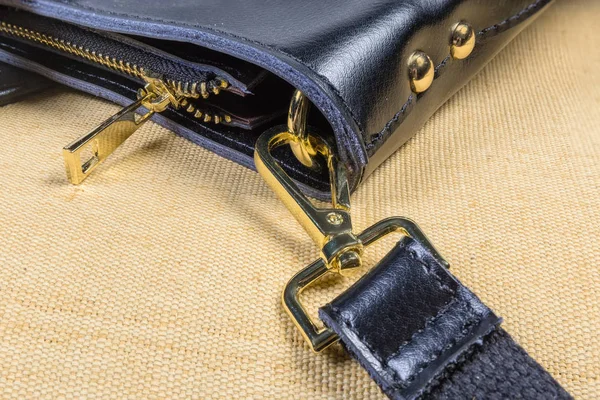 Fragment einer schwarzen Handtasche mit einigen gelben Metalltaschen-Accessoires — Stockfoto