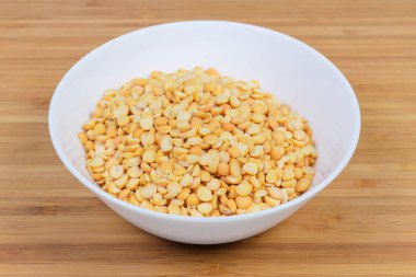 Ahşap bir yüzey üzerinde kabın içindeki sarı bezelyeler.