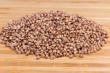 Ahşap yüzeyüzerinde pişmemiş önceden buğulanmış karabuğday groats yığını