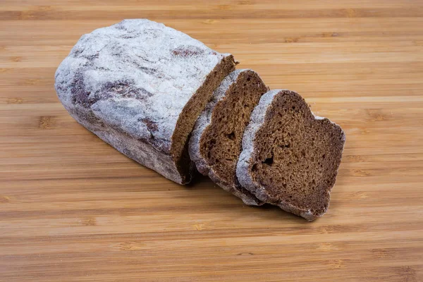 Teilweise geschnittenes braunes Brot auf einem hölzernen Schneidebrett — Stockfoto