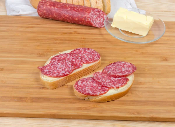 Sandwiches abiertos con salami en tabla de cortar de bambú agains ingredientes — Foto de Stock