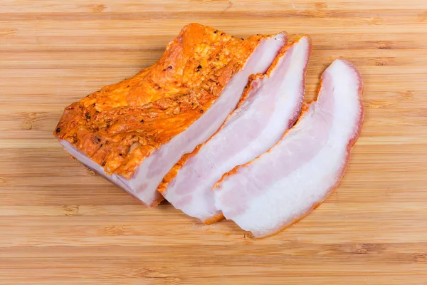 Partly sliced boiled smoked pork belly on wooden cutting board — Stock Photo, Image
