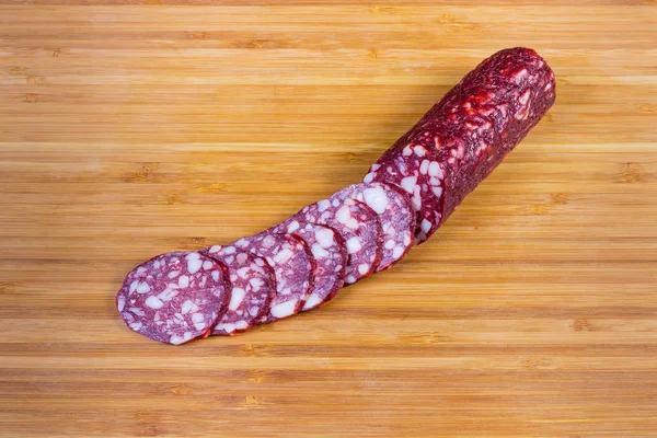 Salsiccia parzialmente tagliata a secco su tagliere di bambù — Foto Stock