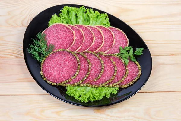 Салями с перцем и пармезановой корочкой на черном блюде — стоковое фото