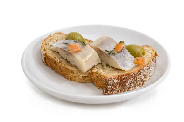Открытый сэндвич с маринованной сельдью и оливками на блюдце — стоковое фото
