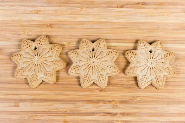 Biscoitos em forma de estrelas em linha na superfície de madeira — Fotografia de Stock