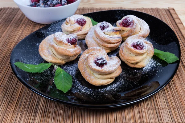 Rolos doces assados e folhas de hortelã no prato preto — Fotografia de Stock