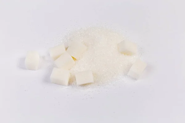 Punhado de açúcar branco e cubos de açúcar na superfície clara — Fotografia de Stock