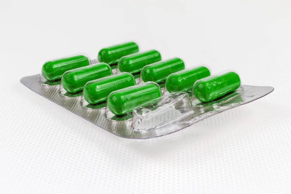 Волдыри пакет с зелеными капсулами таблетки на легкой поверхности — стоковое фото