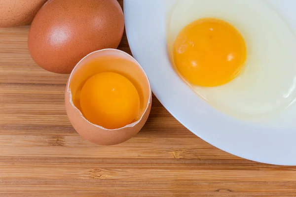 Huevos rotos en cáscara abierta y en plato, vista superior — Foto de Stock