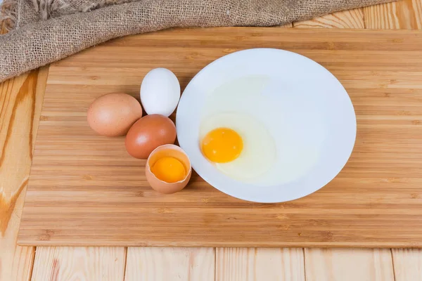 Rozbitá a celá vejce na kůznici na venkovský stůl — Stock fotografie