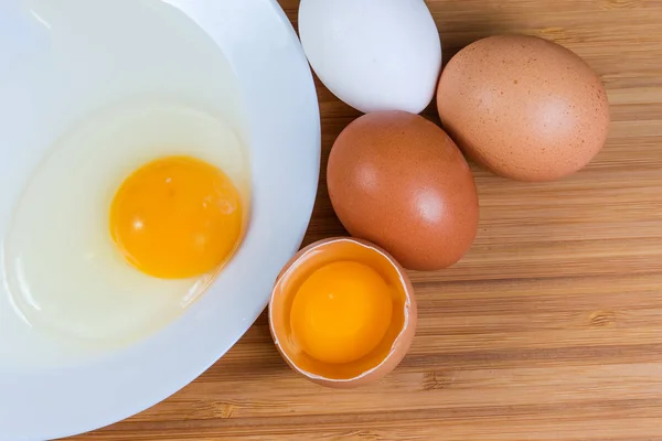 Huevos rotos en cáscara abierta y en plato, vista superior — Foto de Stock