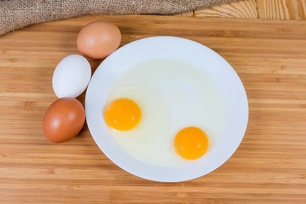 Dvě rozbitá vejce na misku a celá vejce, pohled shora — Stock fotografie