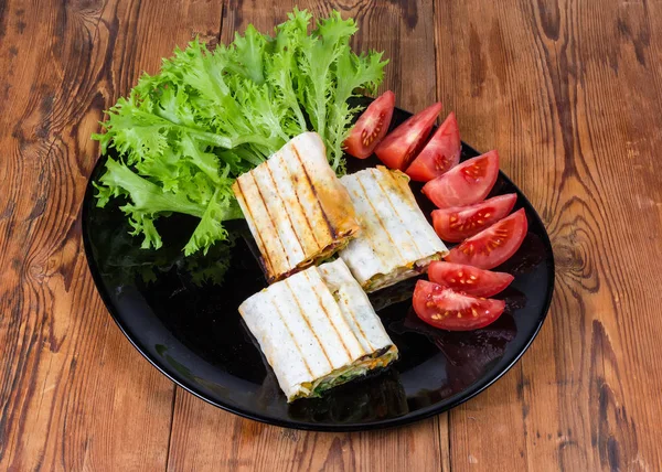 Envoltório de salada de carne grelhada, alface e tomate em prato preto — Fotografia de Stock