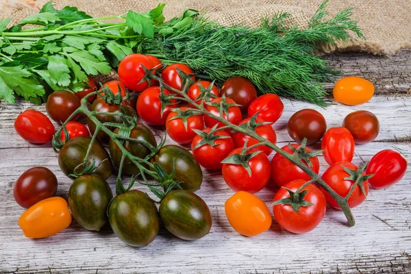 Tomates cerises de couleur variée et légumes frais sur une vieille surface en bois — Photo