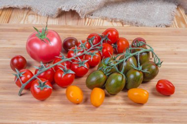 Ahşap kesme tahtası üzerinde farklı kiraz domates ve sıradan domates
