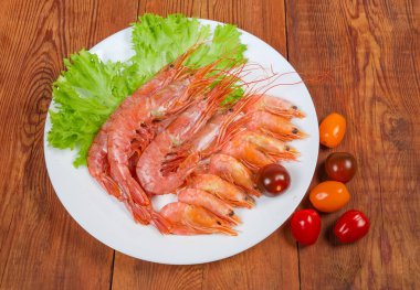 Karides farklı boyutlarda, marul yaprakları ve domates çanak kiraz