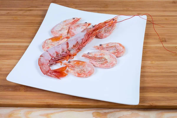Um camarão rei congelado e vários camarões habituais no prato — Fotografia de Stock