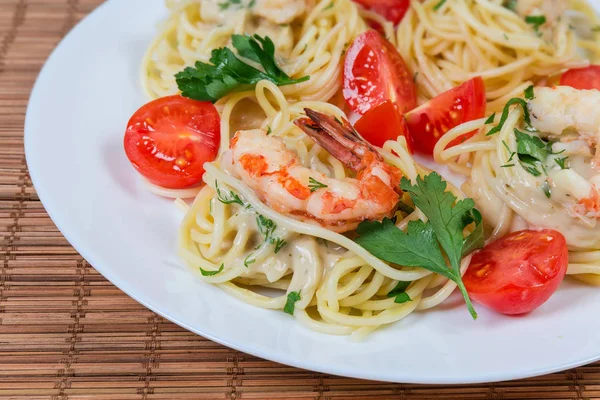 Pasta de espaguetis cocidos con colas de camarón y tomates cherry de cerca — Foto de Stock