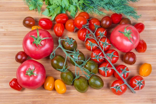 Vue de dessus des tomates ordinaires et cerises sur planche à découper — Photo