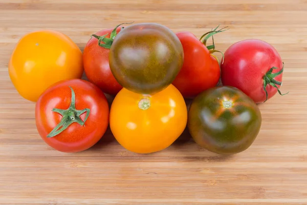 Pile de tomates varicolores sur la planche à découper — Photo