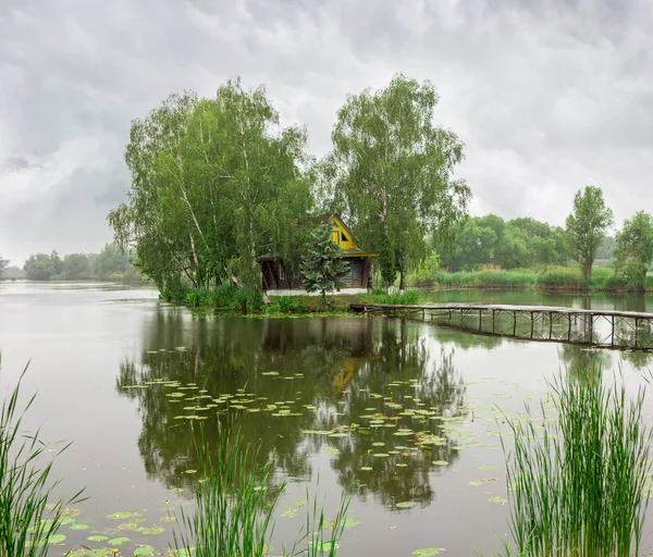 Petite île avec cabane sur le lac et passerelle pendant la pluie — Photo