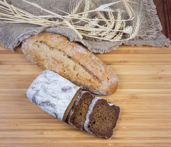 Two varities of brown bread on wooden surface, different ears