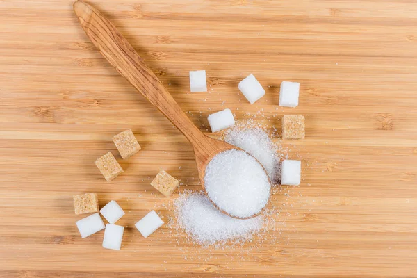 Zucchero bianco in cucchiaio di legno, cubetti di zucchero bianco e marrone — Foto Stock