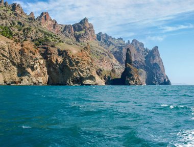 Gökyüzüne karşı denizde volkanik kökeni kıyı kayalıkları