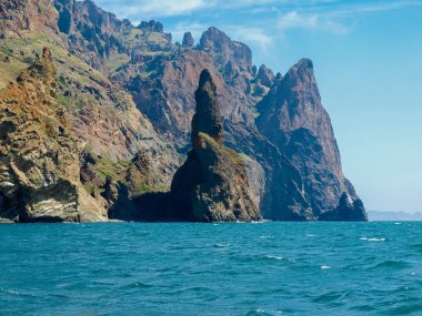 Gökyüzüne karşı denizde volkanik kökeni kıyı kayalıkları