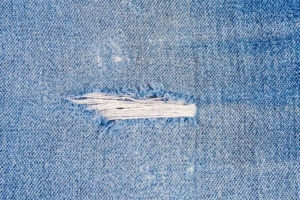 Lugar esfregado em calça azul com fios desgastados close-up — Fotografia de Stock