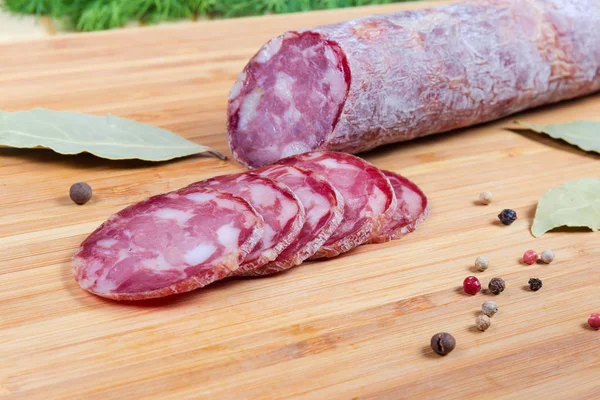 Частково нарізана суха ковбаса серед спецій на обробній дошці — стокове фото