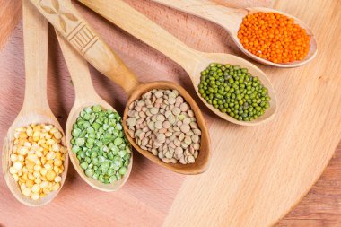 Tahta kaşıklarda çeşitli pişmemiş baklagiller, üst görünüm yakın çekim