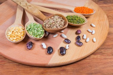 Tahta kaşıklarda ve yanlarında çeşitli pişmemiş baklagiller