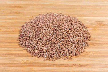 Ahşap yüzeyüzerinde pişmemiş önceden buğulanmış karabuğday groats yığını