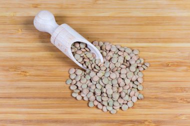 Tahta baharat kaşığı ve onun yanında bütün kahverengi mercimek