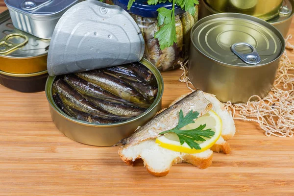 Sprats în cutie de staniu deschisă, sandwich deschis împotriva altor cutii — Fotografie, imagine de stoc